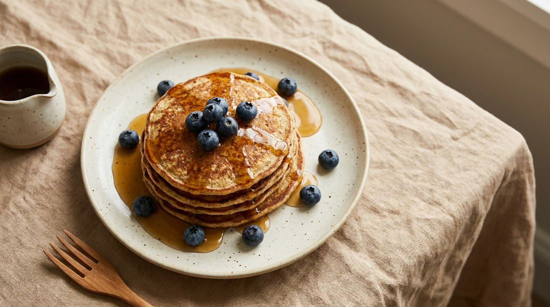 Stack of golden oat pancakes with maple syrup and blueberries